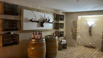 Una habitación rústica con barriles de madera, botellas de vino y cajas en las paredes.