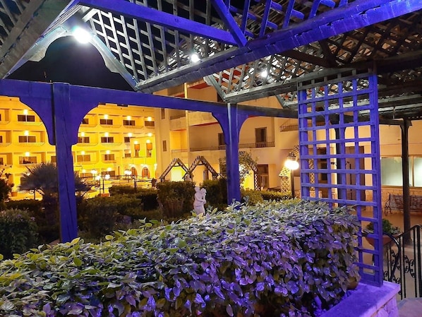 Ein Hotelinnenhof mit überdachter Sitzgelegenheit, einer Statue und einem Gebäude mit mehreren Balkonen.