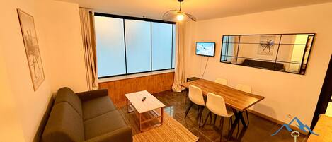 Una sala de estar moderna con un sofá, una mesa de centro, un televisor y un comedor con sillas.