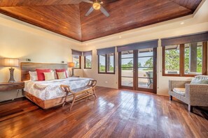A spacious bedroom with a large bed, a wooden ceiling, and a view through glass doors. - Naka-Mar Beachfront Villa (Las Golondrinas , Hacienda Pinilla)