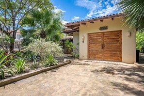 A house with a double wooden door, a number '7' sign, and a garden with various plants. - Naka-Mar Beachfront Villa (Las Golondrinas , Hacienda Pinilla)
