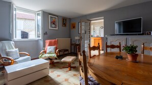 Ein Essbereich mit Holztisch, Stühlen, einem Blumentopf und einem Fernseher.