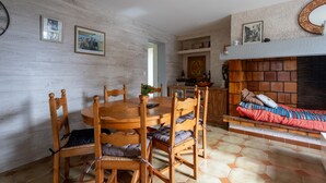 Ein Essbereich mit Holztisch und -stühlen, einer kleinen Pflanze und einem Kamin mit Ziegelverkleidung.