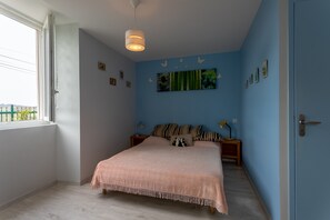 Une chambre à coucher avec un lit, des tables de chevet, une lampe suspendue et une fenêtre.