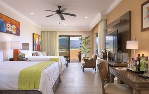 Quarto de hotel com duas camas, uma mesa com cadeira, televisão e varanda com vista para as montanhas.
