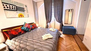A bedroom with a bed, pillows, a bedside table, a mirror, and a window with curtains. - Liberty apartment, Porta Susa center, wifii flat, parking, pets allowed (Torino)