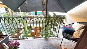 A balcony with a metal railing, a chair with cushions, and potted plants. - Liberty apartment, Porta Susa center, wifii flat, parking, pets allowed (Torino)