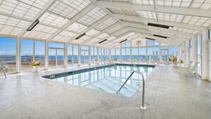 Piscina interna com vista clara para o oceano, grandes janelas e teto alto com claraboias.