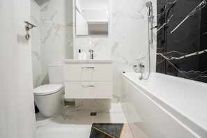 A modern bathroom with a toilet, vanity, and bathtub.