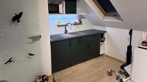 Eine kleine Küche mit Einbauofen, Spüle und einem Fenster über der Arbeitsfläche.