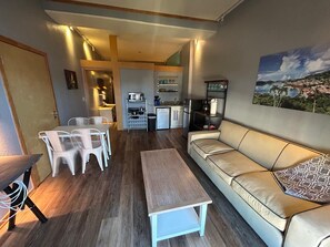 A compact living space with a dining area, kitchenette, and a sofa.