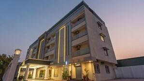 A multi-story hotel with a modern design, featuring balconies, a covered entrance, and a well-lit facade. - Treebo Premium Pine Tree Courtyard (Chennai)