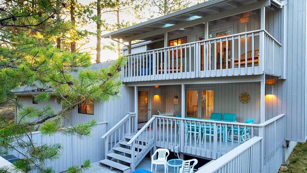 A two-story wooden house with a balcony, outdoor seating, and a hot tub. - 5 Lark-Sunriver, Oregon: Hot Tub, A/C, BBQ, WiFi, SHARC Aquatics, Tubing Hill, Mt. Bachelor, Golf, Deschutes River, Tennis, Bike Paths (Sunriver)