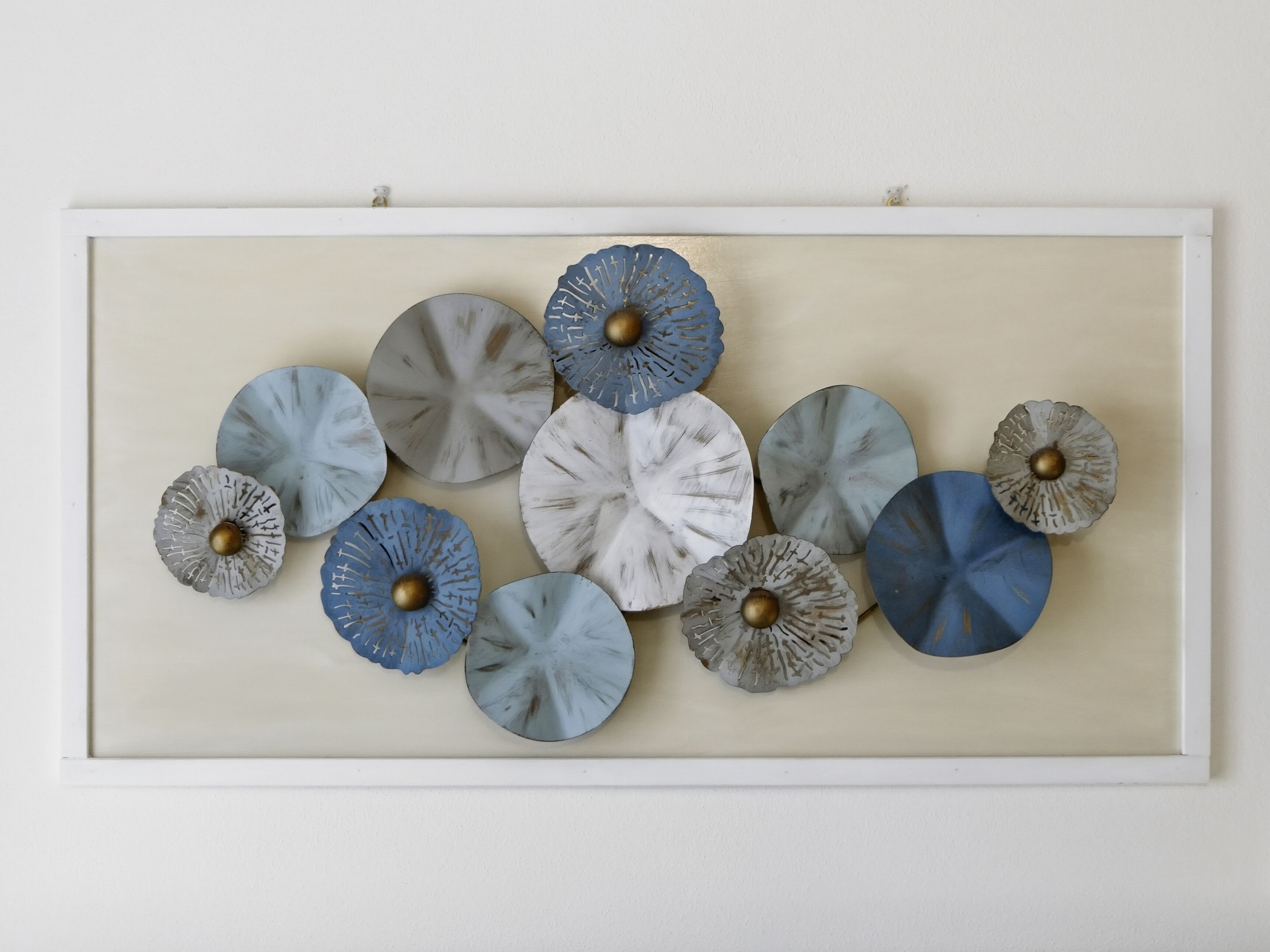 A framed collection of circular decorative pieces with metallic centers, arranged on a wall.