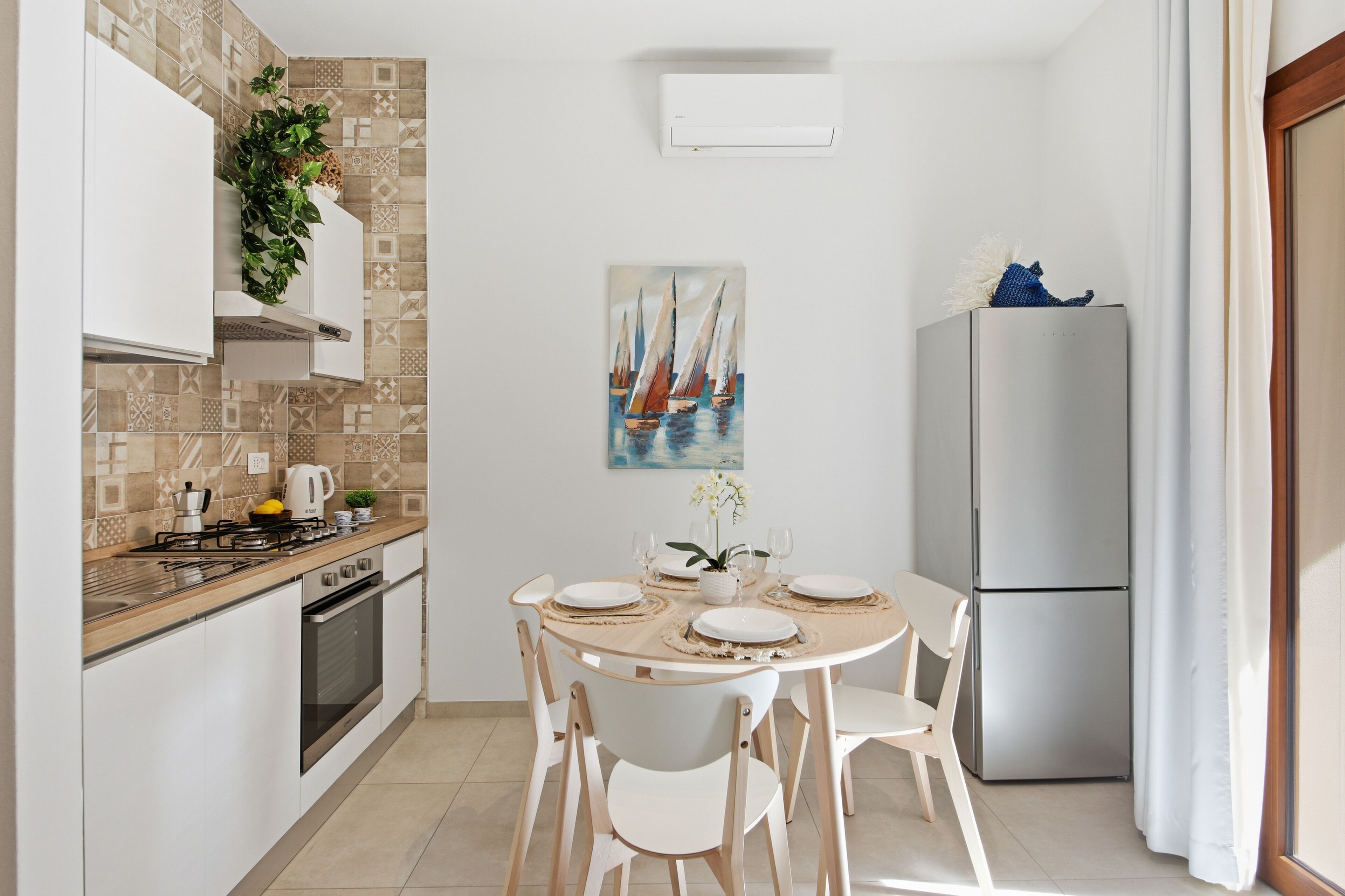 A compact kitchen with a dining area, a refrigerator, and a painting on the wall.