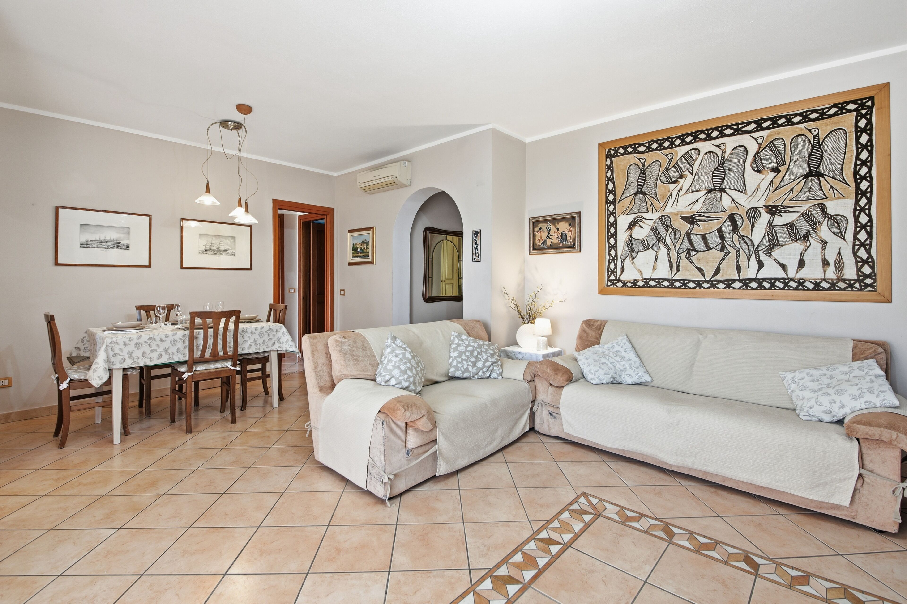 Uma sala de estar com sofá, mesa de jantar, cadeiras e obras de arte nas paredes.