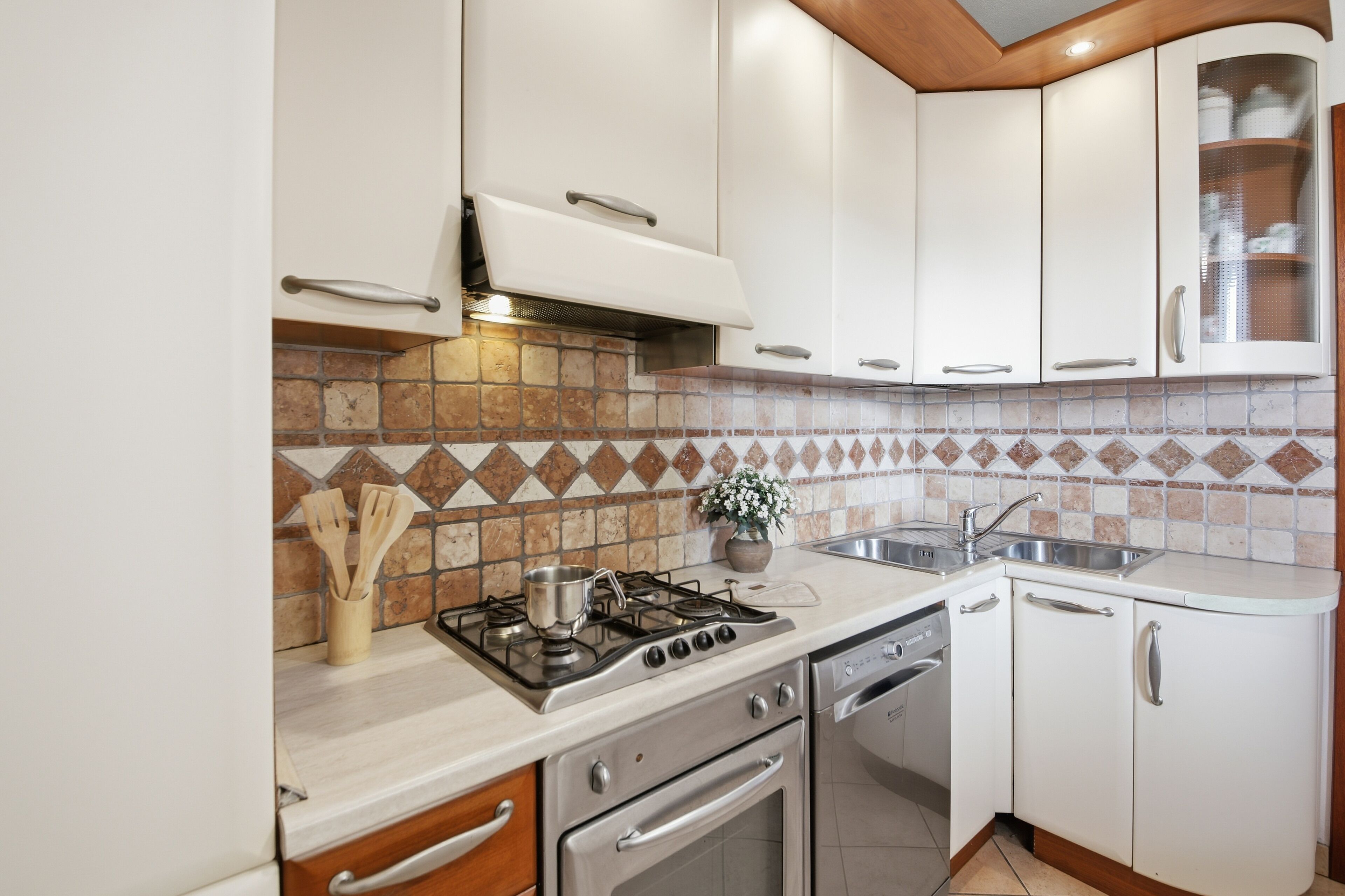 A kitchen with white cabinets, a gas stove, a dishwasher, and a tiled backsplash.