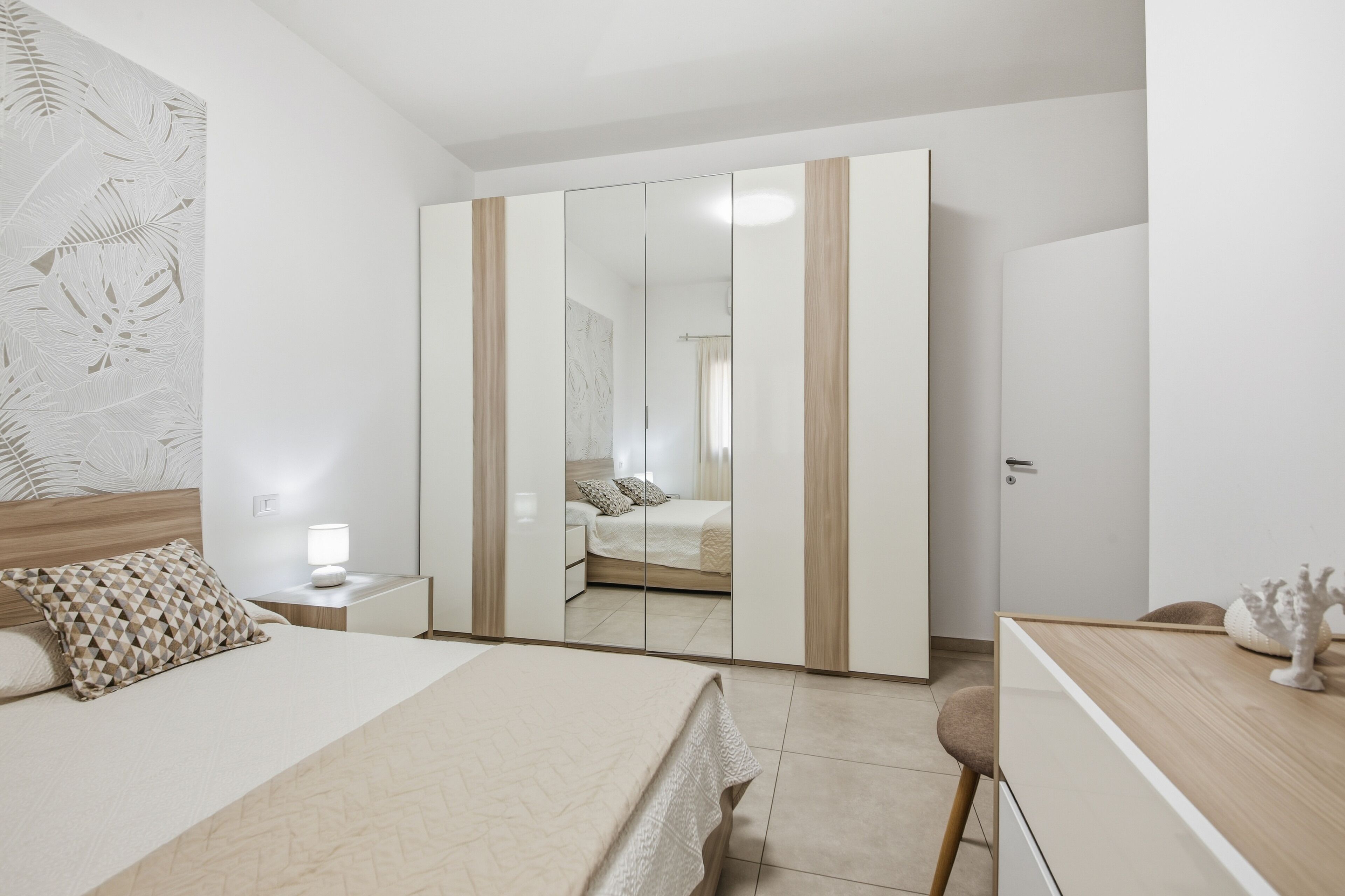 Une chambre moderne avec un lit, une table de chevet et une armoire dotée d’un miroir.