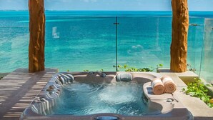Un bain à remous avec vue sur l’océan, entouré d’arbres et doté d’une balustrade en verre.