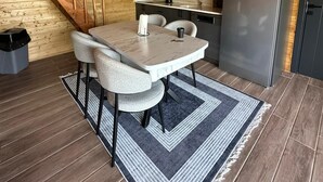 Una cocina compacta con zona de comedor, vigas de techo de madera y un refrigerador moderno.