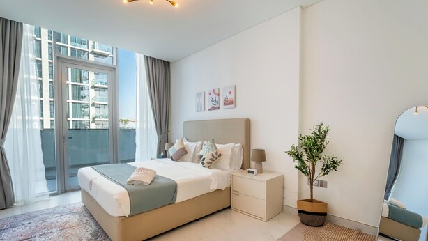 A modern bedroom with a large bed, bedside tables, a nightstand, a potted plant, and a view of the outside. - Manzil - 2BR w City View near Dubai Mall (Dubai)