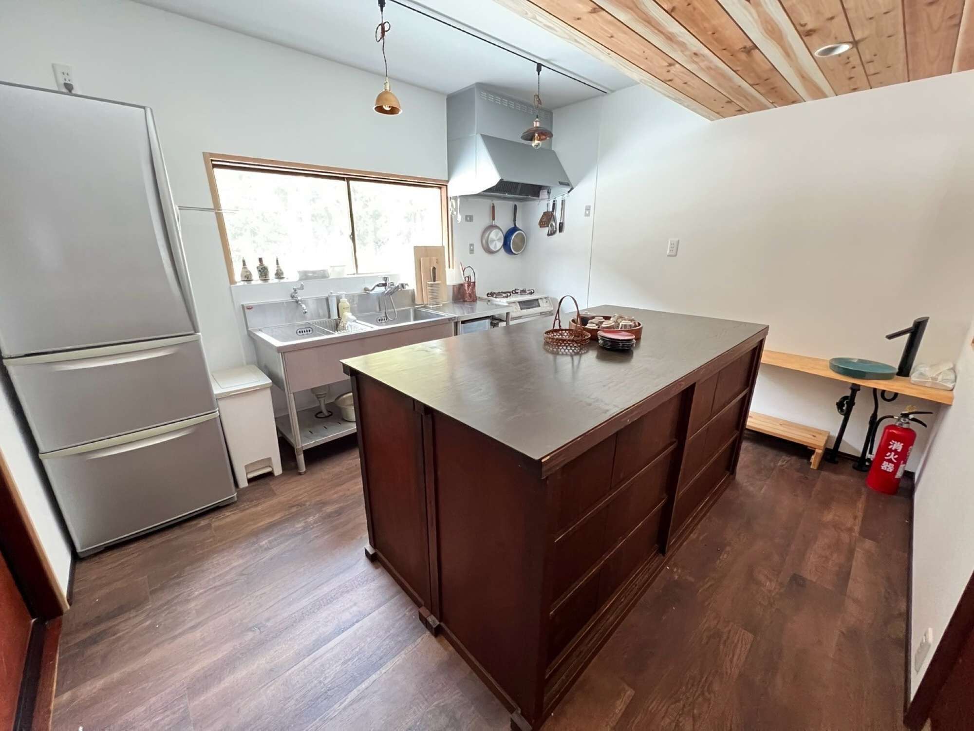 Una cocina moderna con una isla grande, electrodomésticos de acero inoxidable y techo de madera.