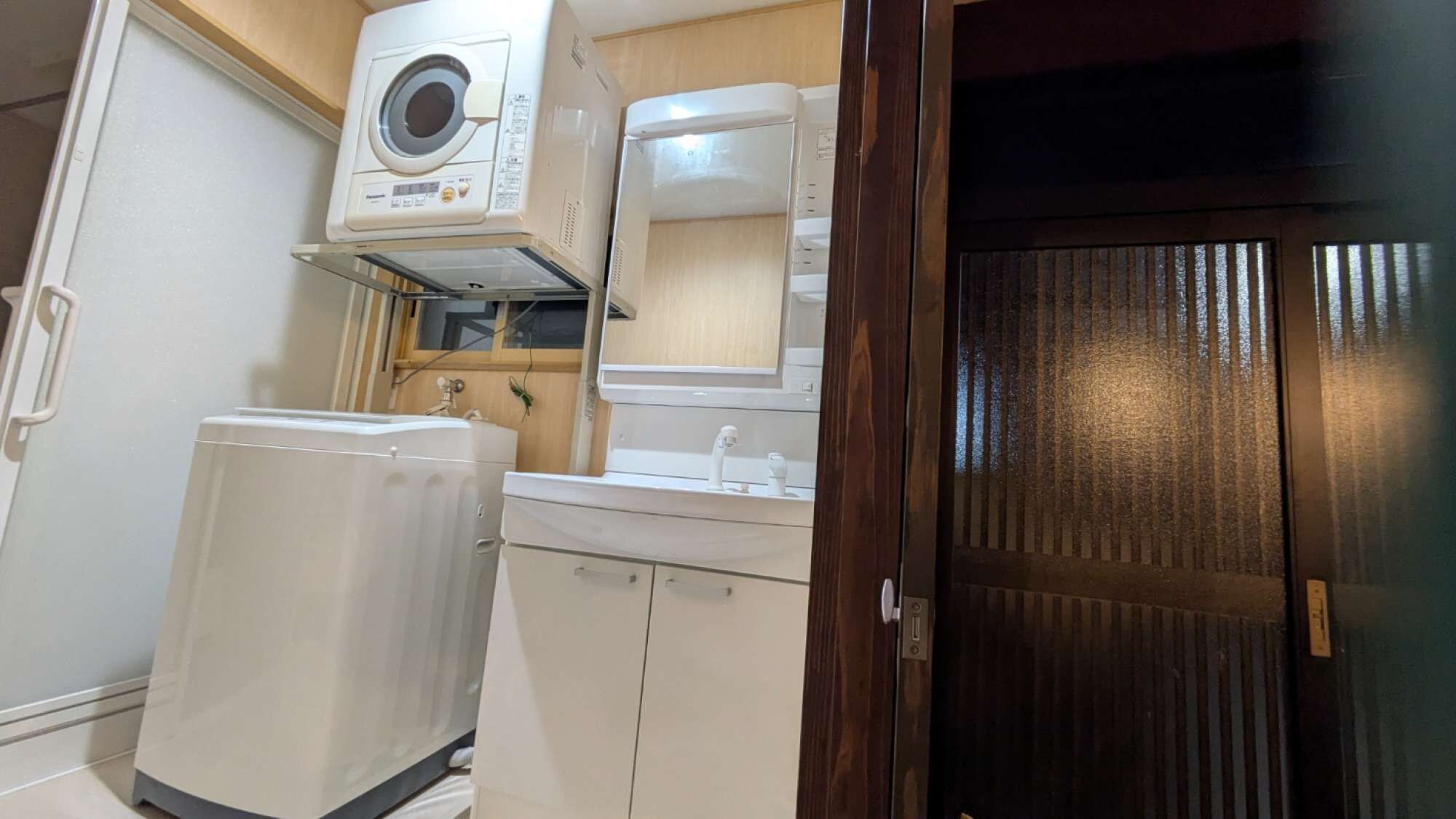 A compact kitchen with a built-in washer, a sink, and a wooden door.