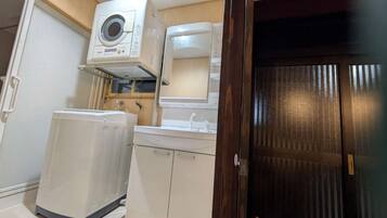 A compact kitchen with a built-in washer, a sink, and a wooden door.