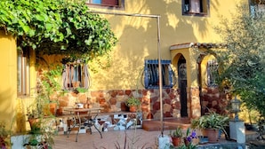 A courtyard with a stone wall, potted plants, a table, and a bench.