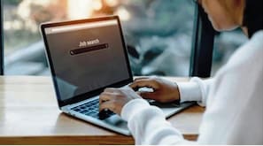 A person using a laptop with a job search screen on the display.