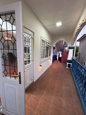 A corridor with a white door, barred windows, and a staircase leading to an upper level. - Calm Nest 3-bedroom Apartment. 180m from the beach. Family and Business Trips! (Flic en Flac)