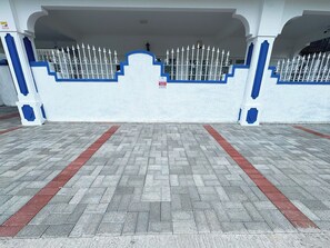 A gated entrance with a white and blue color scheme, a paved walkway, and a sign indicating parking availability. - Calm Nest 3-bedroom Apartment. 180m from the beach. Family and Business Trips! (Flic en Flac)