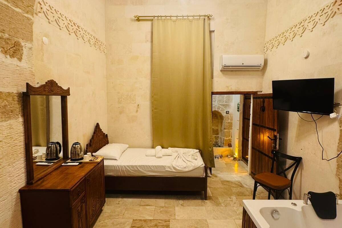 Ein Schlafzimmer mit Bett, Kommode, Fernseher und einem Badezimmer mit Badewanne und Waschbecken.