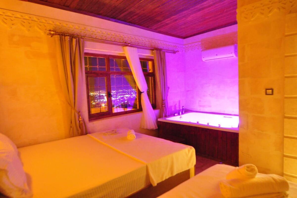 Ein Hotelzimmer mit Bett, einem Vorhangfenster, einer Badewanne und Blick auf die Stadt.