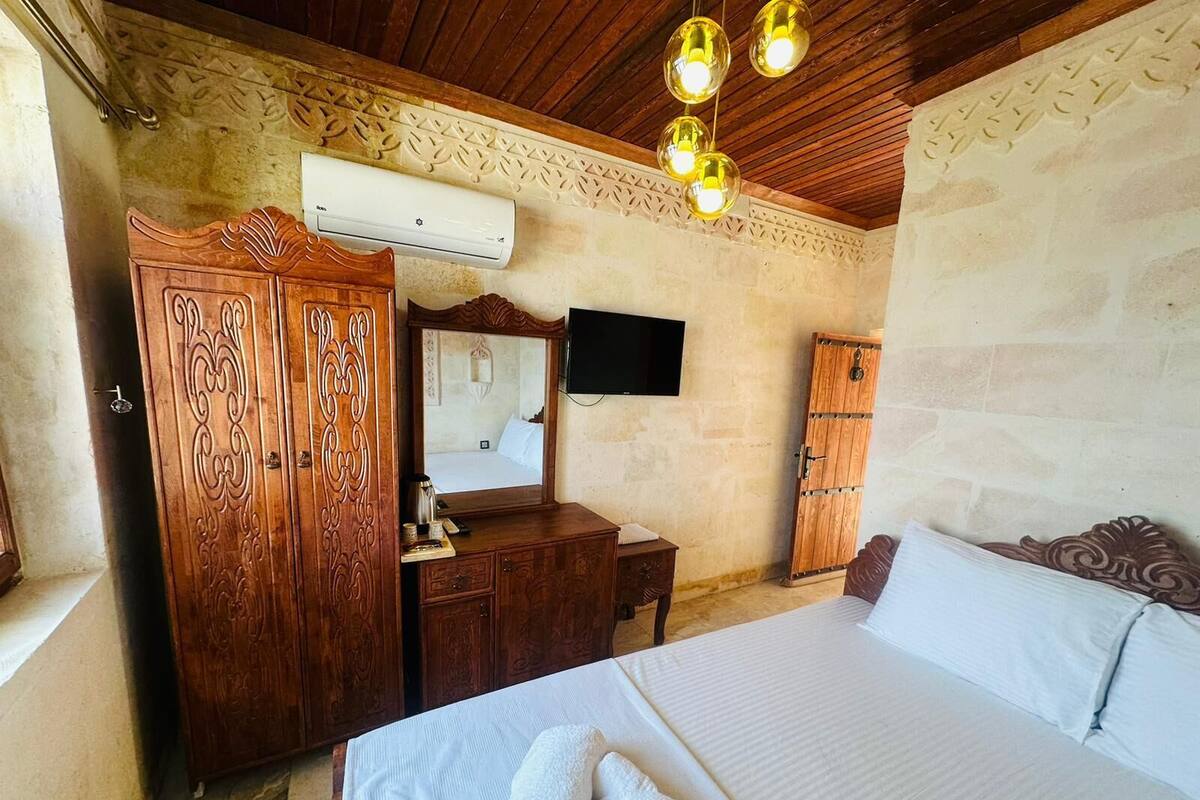 Ein Schlafzimmer mit einem Bett, einem Holzschrank, einer Kommode, einem Flachbildfernseher und einer Klimaanlage.