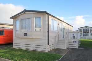 A mobile home with a front porch and a small staircase leading to the entrance.