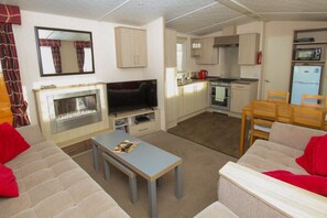 A compact living space with a TV, sofa, dining table, kitchen area, and a fireplace.