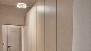 Un pasillo con suelo de madera, una puerta al final e iluminación en el techo.