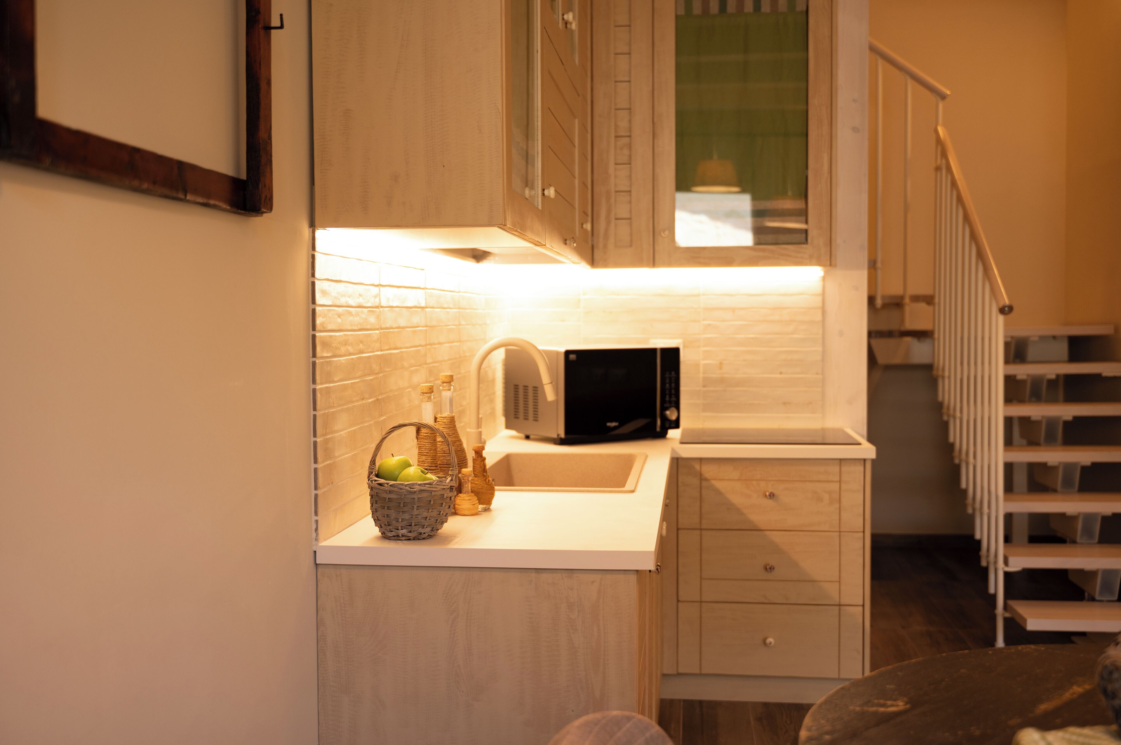 Una cocina compacta con microondas, fregadero y una pequeña encimera.
