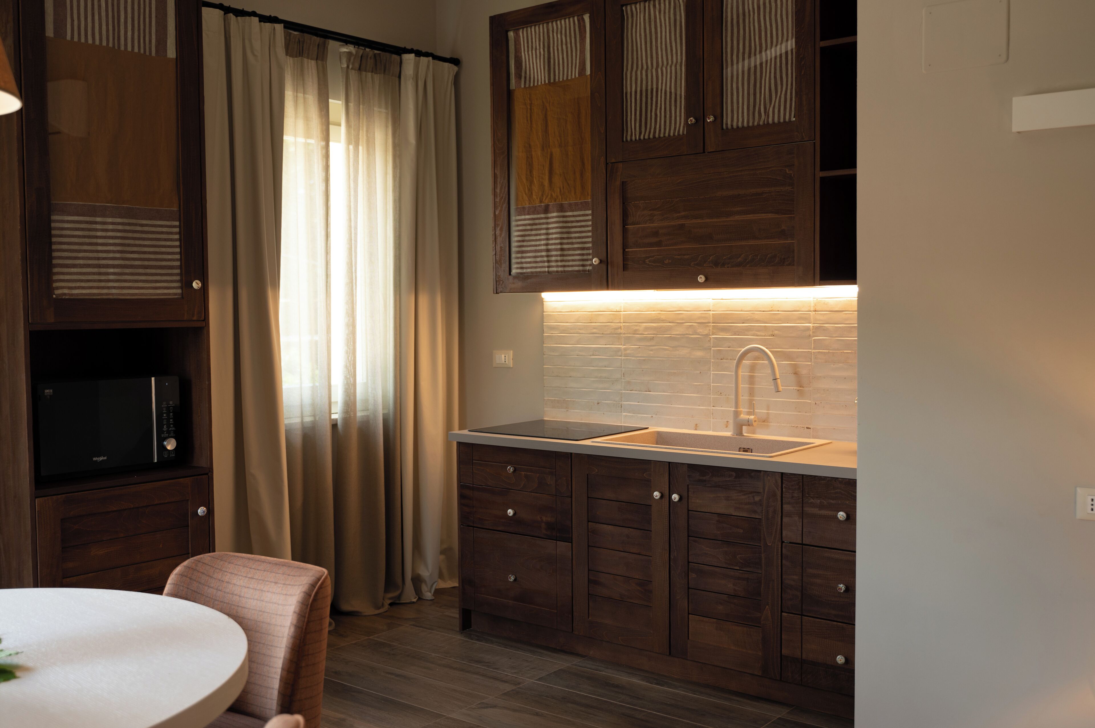 A modern kitchen with wooden cabinets, a built-in microwave, a sink, and a round dining table.