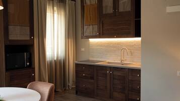 A modern kitchen with wooden cabinets, a built-in microwave, a sink, and a round dining table.