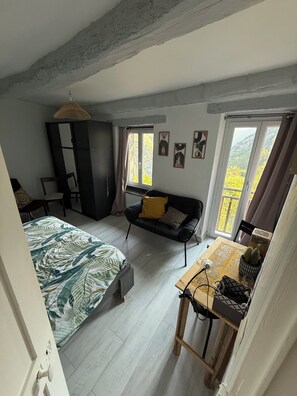 A bedroom with a bed, a sofa, a desk, and a wardrobe. There are windows with curtains and a view of greenery outside. - Balcon soleil, a haven of peace with a sublime view (Malaussène)