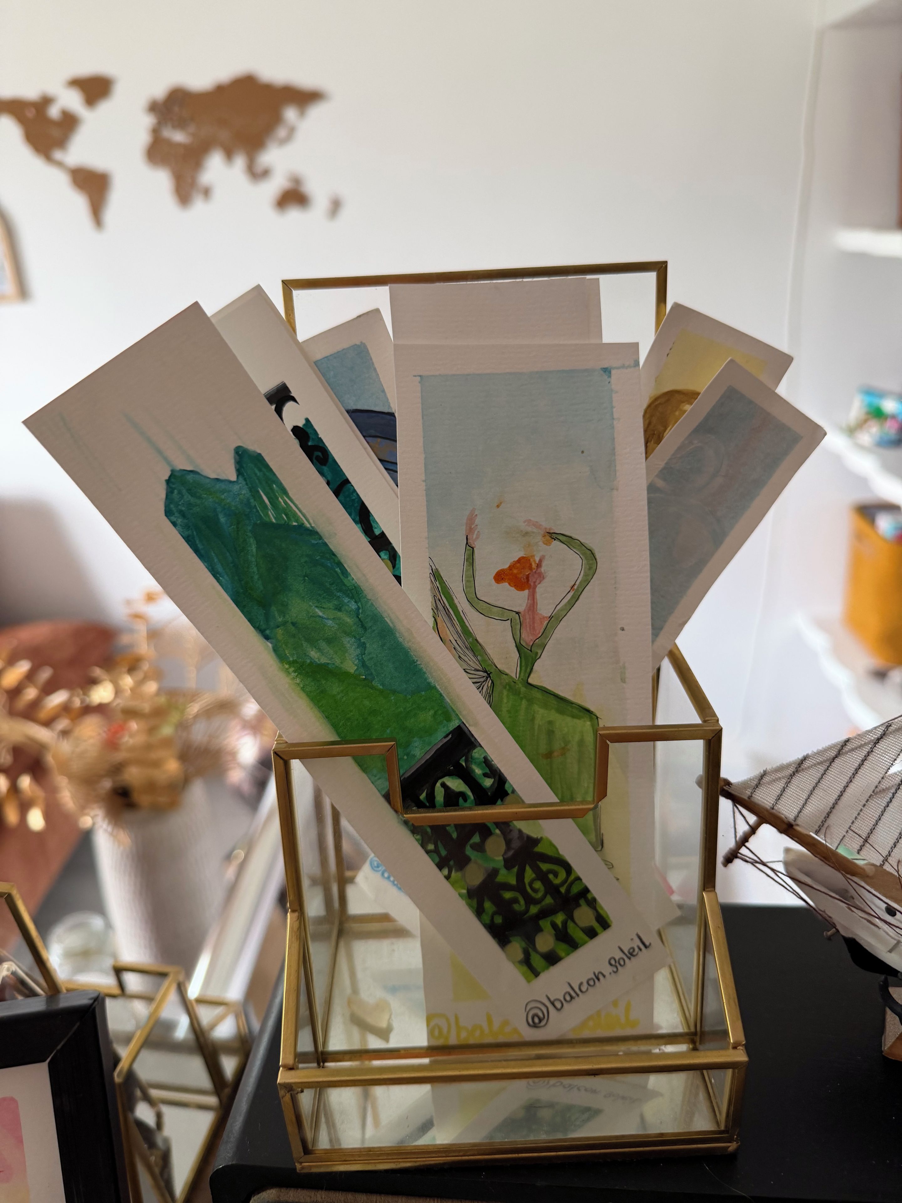 Un présentoir où sont exposées diverses œuvres d’art, dont un tableau représentant un cactus.