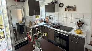 Eine moderne Küche mit dunklen Holzschränken, einer weißen Arbeitsplatte und einem großen Fenster.