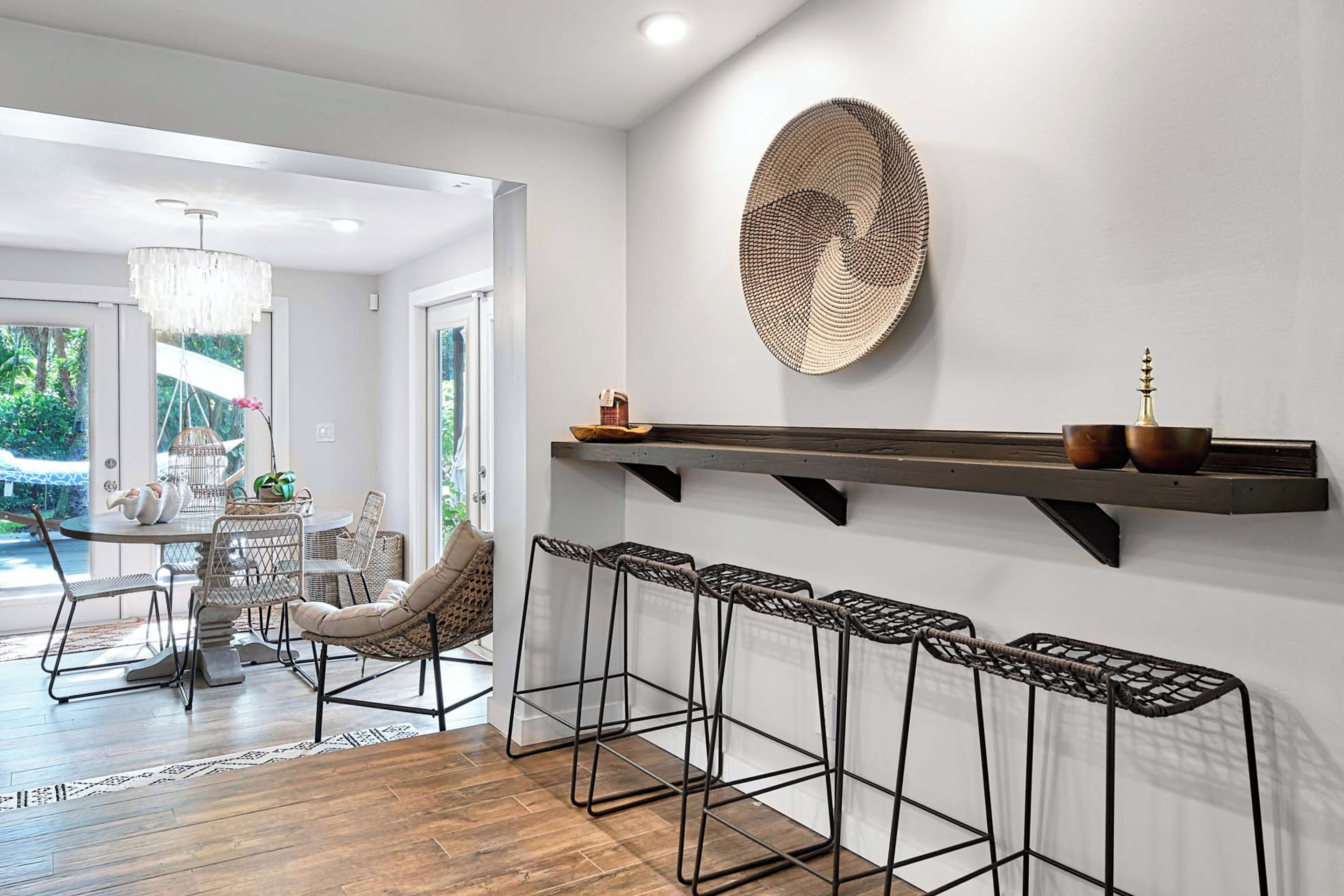 A modern interior with a dining area, bar stools, and a decorative wall piece.