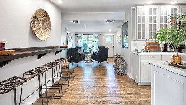 A modern kitchen with white cabinets, a wooden bar counter, and a seating area with chairs and a table. - Near Old Naples! Coastal Escape w/ Tropical Patio (Naples)