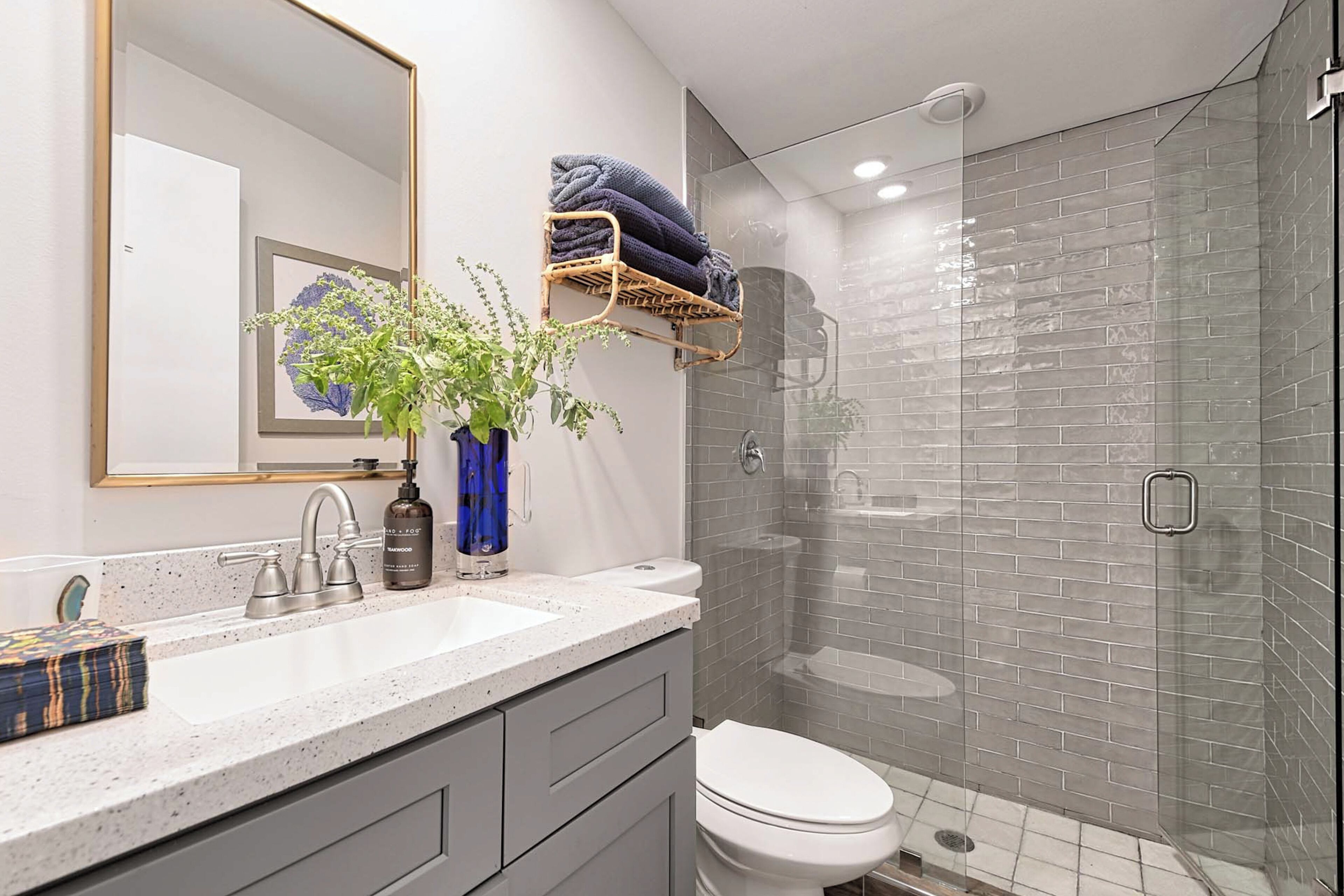 A bathroom with a white sink, a mirror, a toilet, and a glass-enclosed shower.