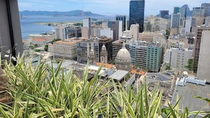 A cityscape with a mix of modern and historical buildings, a prominent dome structure, and a view of the sea. - Modern apartment in Rio de Janeiro + swimming pool + rooftop with panoramic views. (Rio de Janeiro)