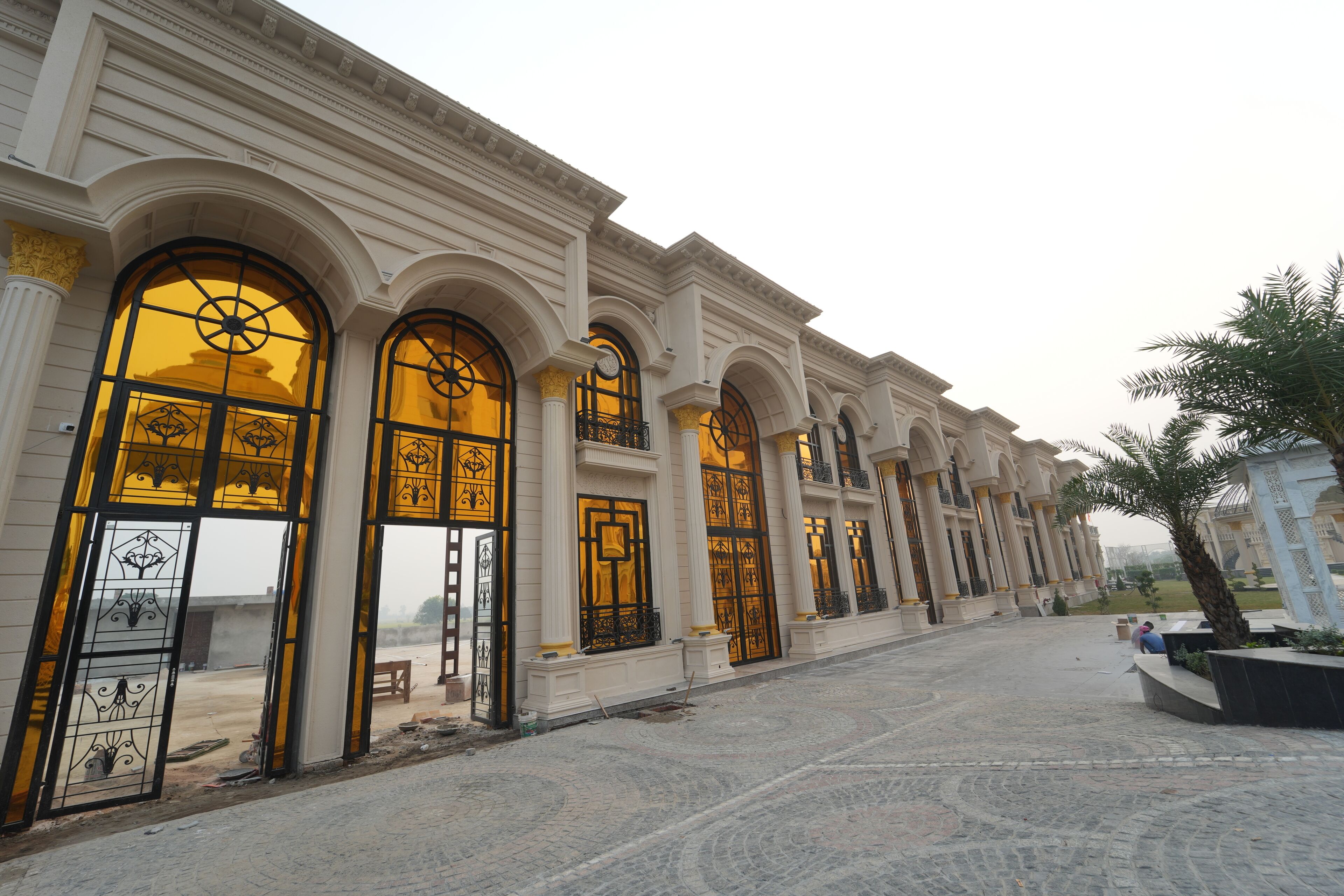A building with large arched windows and a paved courtyard.