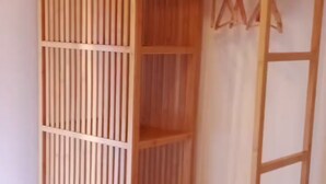 A room with a wooden wardrobe, a bed with patterned bedding, and a hanging clothes rack.